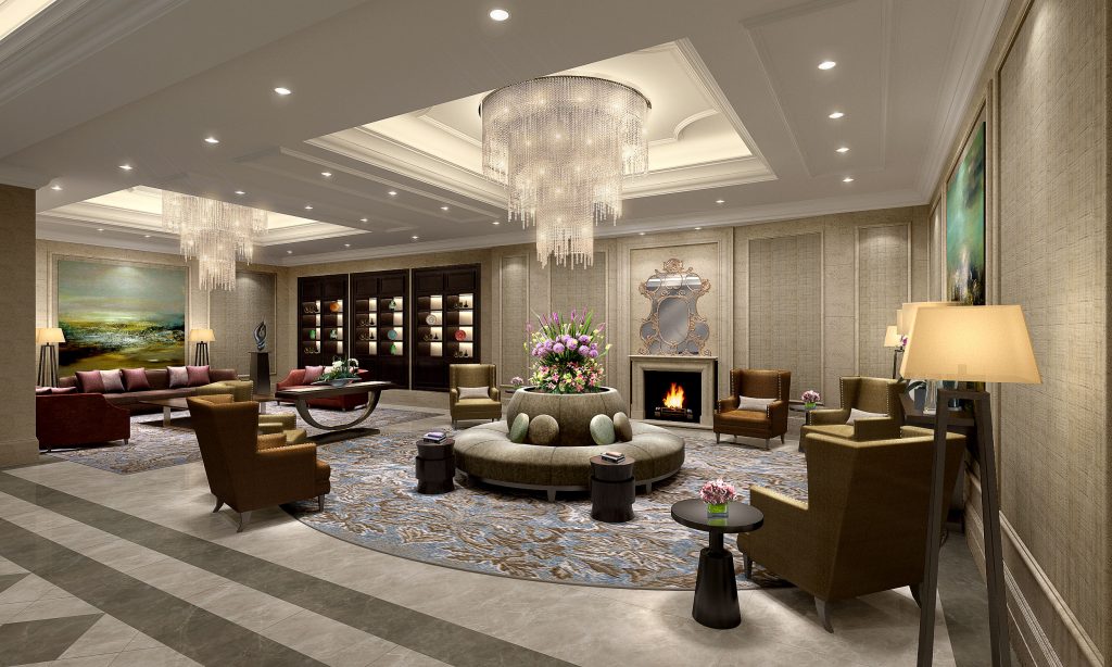 Elegant hotel lobby lounge with crystal chandeliers, a circular tufted sofa, leather armchairs, fireplace with ornate mirror, and floral centerpiece on a patterned round rug.